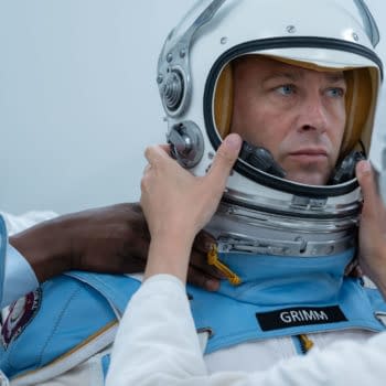 In a scene from 'The Fantastic Four: First Steps,' Ebon Moss-Bachrach portrays Ben Grimm/The Thing as he is assisted by crew members in putting on a space suit helmet in a futuristic setting.