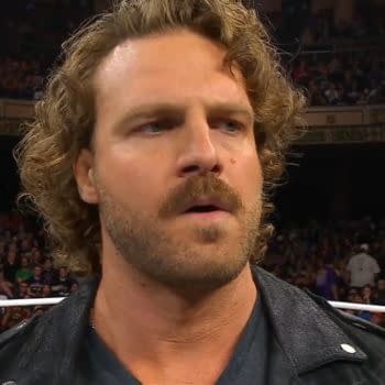 Hangman Adam Page, a professional wrestler, appears on stage at AEW Dynamite, displaying a serious expression with a crowd in the background.