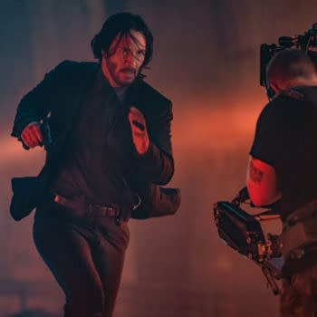 Keanu Reeves as John Wick running in a dramatic scene from John Wick: Chapter 4, with a film camera operator capturing the action in a moody, lit environment.