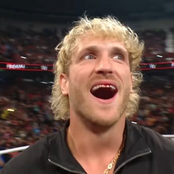 Logan Paul stands with a wide smile, looking energized and confident at the end of a WWE Raw event, with a cheering crowd in the background.