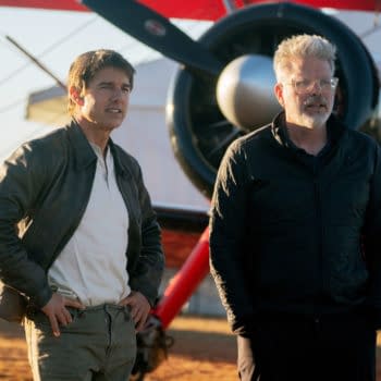 Tom Cruise and Christopher McQuarrie stand on the set of 'Mission: Impossible - The Final Reckoning' in front of a biplane during sunset, with a warm light illuminating the scene.