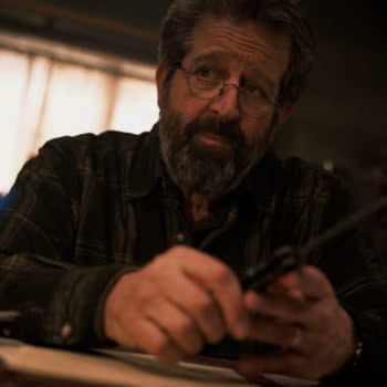 A scene from 'Mission: Impossible - The Final Reckoning' featuring Rolf Saxon as William Donloe, who appears contemplative while holding a pair of scissors in a dimly lit room.