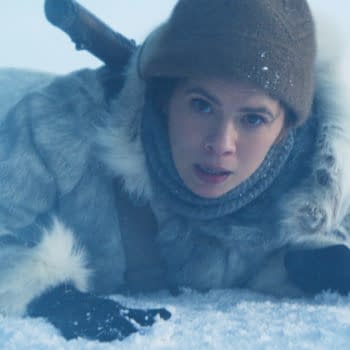 A scene from 'Mission: Impossible - The Final Reckoning' featuring Hayley Atwell as Grace, dressed in a fur coat and hat, lying in a snowy, icy environment, with a look of determination on her face.