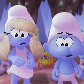 A scene from the animated movie "Smurfs," featuring the characters Smurfette, Brainy Smurf, and Ken. Smurfette has blonde hair and a worried expression, while Brainy Smurf looks concerned, set against a colorful background with other Smurf characters in the scene.