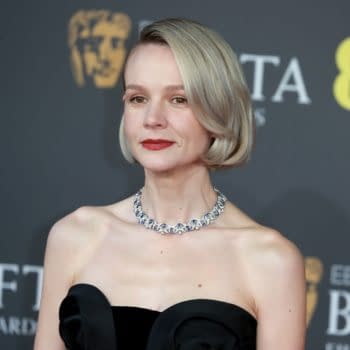 A portrait of actress Carey Mulligan at the BAFTA Film Awards, wearing a black strapless dress and a sparkling necklace, with a neutral background featuring BAFTA logos.
