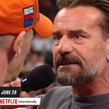 Two men, CM Punk and John Cena, are depicted in a tense face-off during a wrestling promo, with CM Punk speaking passionately into a microphone. The backdrop suggests an event taking place in Saudi Arabia, highlighting their upcoming match.