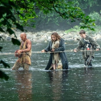 Three characters wade through shallow water, using a rope for support. The scene conveys a sense of survival and struggle, with one individual appearing dirty and rugged, another in a wool coat, and a younger person holding a makeshift weapon.