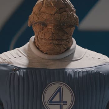 Ebon Moss-Bachrach portrays Ben Grimm, also known as The Thing, in a blue and white superhero suit featuring the number four emblem, from the Marvel Studios film "The Fantastic Four: First Steps." The character has a textured, rocky appearance.
