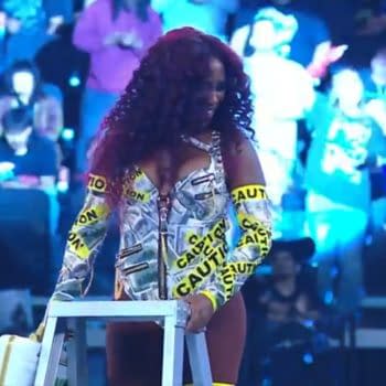 Naomi celebrates her victory in the 2025 Money in the Bank ladder match, wearing a vibrant outfit adorned with money prints and 'Caution' labels, while holding a ladder.