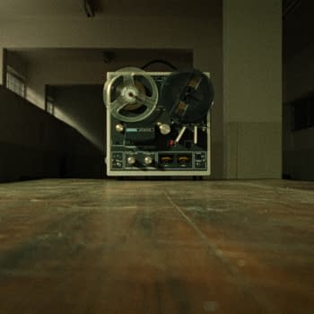 A vintage reel-to-reel tape recorder sits on a wooden table in an empty room with dim lighting. It symbolizes the chilling recordings related to the Son of Sam case.