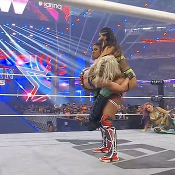Athena performs a wrestling move, holding two women in the ring during the AEW All In Texas Casino Gauntlet match, with dramatic lighting and an excited crowd in the background.