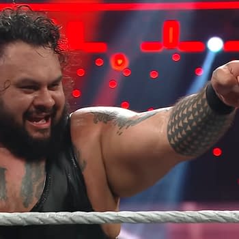 Bronson Reed, a professional wrestler, appears on WWE Raw, passionately pointing while celebrating in the ring. He has long curly hair and visible tattoos on his arms and chest.