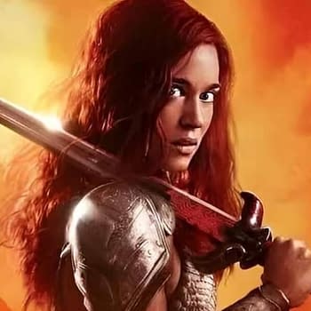 A fierce warrior with long red hair stands confidently, holding a sword with a decorative hilt against a dramatic orange background, conveying a sense of action and adventure.
