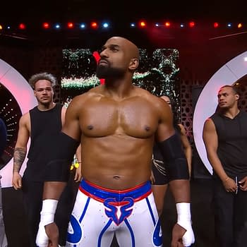 Scorpio Sky is center stage at AEW Collision 100, flanked by Christopher Daniels, Leila Grey, and members of Top Flight. Scorpio is wearing distinctive wrestling gear featuring a blue and white design, with the others dressed in black.