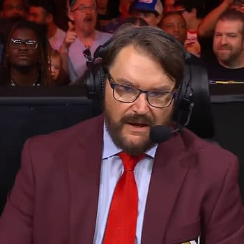 Tony Schiavone, wearing a maroon blazer and a red tie, speaks into a microphone while discussing Hulk Hogan's death on AEW Collision. The crowd is visible in the background, showing various reactions.