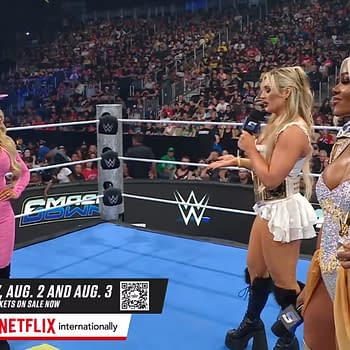 Trish Stratus, Tiffany Stratton, and Jade Cargill stand in a wrestling ring on WWE SmackDown, with a packed audience visible in the background. Each performer showcases distinctive outfits, with Stratus wearing a pink ensemble and a cowboy hat, Stratton in a white costume, and Cargill in a sparkling silver outfit.