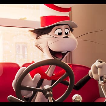 A cheerful animated cat wearing a tall red and white striped hat is sitting at the wheel of a car, smiling widely. The car's interior is bright red, with a window showing raindrops in the background.