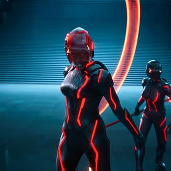 Jodie Turner-Smith as Athena stands confidently in a futuristic setting, wearing a sleek black suit with glowing red lines. Two other characters in similar outfits accompany her, set against a backdrop of illuminated structures and a staircase.