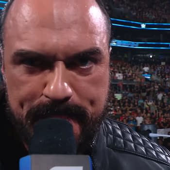 Drew McIntyre delivers a passionate promo on WWE SmackDown, holding a microphone close to his face in front of a large crowd. The excitement of the audience is palpable in the background.