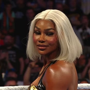 Jade Cargill stands in the wrestling ring on WWE SmackDown with a confident expression, wearing a black and gold outfit. The background features an audience applauding and cheering for her performance.
