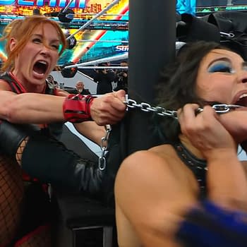 A wrestler with red hair in a black outfit, Becky Lynch, aggressively pulls a chain attached to another wrestler, Lyra Valkyrie, who appears to be in distress. The background shows a wrestling ring surrounded by fans at WWE SummerSlam.