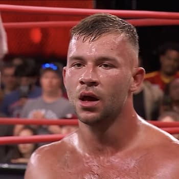 Daniel Garcia stands in a wrestling ring, visibly torn between two individuals, with an audience in the background. His expression conveys conflict and uncertainty.