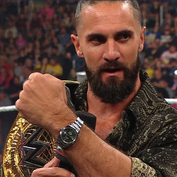 Seth Rollins shows off the WWE Championship belt while addressing the crowd on WWE Raw, wearing a stylish patterned shirt and a watch.