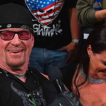 The Undertaker and Stephanie McMahon share a moment at WWE WrestlePalooza, with McMahon announcing her induction into the 2026 Hall of Fame class. The Undertaker is wearing a bandana and sunglasses, showing a playful demeanor.
