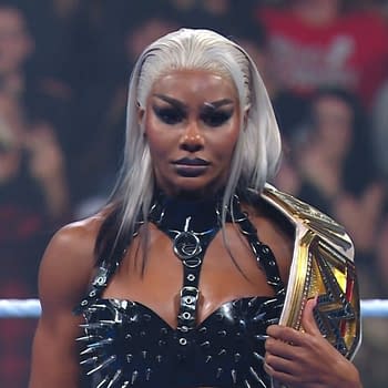 Jade Cargill poses confidently on WWE SmackDown, wearing a black spiked outfit and holding a championship belt, amidst an engaged crowd.