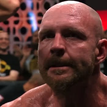 Jon Moxley, a professional wrestler, displays a serious expression as he reacts to a moment in AEW Collision, with fans visible in the background responding to the scene.