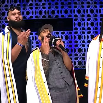 Three wrestlers on stage at AEW Dynamite, with one man passionately speaking into a microphone. They are dressed in stylish outfits with colorful accents and show a range of emotions.