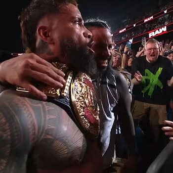 The Usos embrace each other, celebrating while wearing the Tag Team Championship belts after their victory on WWE Raw. The excited crowd can be seen in the background, capturing the energy of the moment.