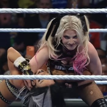 Alexa Bliss prepares to execute the Sister Abigail DDT on her opponent in a WWE SmackDown match, showcasing her intense focus and competitive spirit. The audience is visibly engaged in the background.