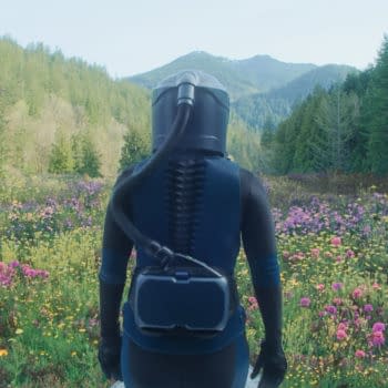 A character in a protective suit stands in a vibrant field of flowers, surrounded by lush greenery and mountains in the background, evoking a sense of exploration and adventure. This scene is connected to the film 'In The Blink Of An Eye'.