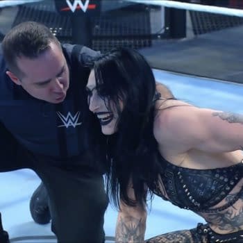 Rhea Ripley, wearing a black outfit with tattoos visible, celebrates her victory in the Elimination Chamber, smiling and engaging with a referee.