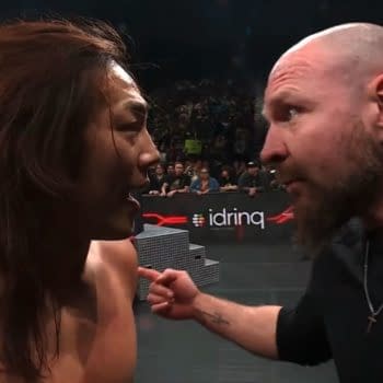Konosuke Takeshita and Jon Moxley face each other intensely in the ring during AEW Collision, showcasing a confrontation filled with emotion. The backdrop features a wrestling ring and an audience in the stands.