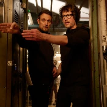 Directors Matt Bettinelli-Olpin and Tyler Gillett discussing a scene on the set of 'Ready Or Not 2: Here I Come', standing in a dimly lit room filled with lockers and equipment.