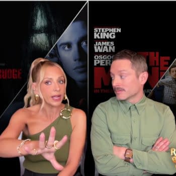 Sarah Michelle Gellar and Elijah Wood discuss horror films, with promotional images of 'The Grudge' and 'Ready Or Not 2' in the background. Gellar is gesturing with her hands while wearing a stylish top and large earrings, while Wood looks attentively at her.