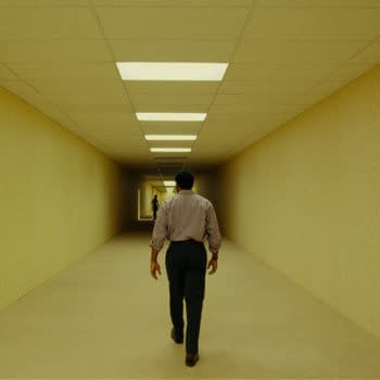 A lone man walks down a long, eerie yellow hallway with fluorescent ceiling lights, evoking the Backrooms. Another figure stands far ahead in the distance.
