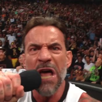 A man with a microphone passionately delivers a speech, showcasing intense emotions with a focused expression. A crowd of enthusiastic fans surrounds him, reacting with excitement in a vibrant arena.