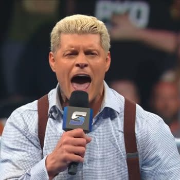 Cody Rhodes passionately delivers a heated promo on WWE SmackDown, holding a microphone while wearing a button-up shirt with suspenders. The audience is visible in the background, showing their engagement.