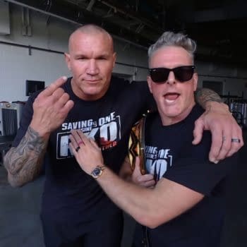 Randy Orton and Pat McAfee pose closely together in a backstage area, with Orton raising one finger, while McAfee has an excited expression and holds a WWE Championship belt. Both wear matching black T-shirts featuring the phrase 'Saving is One' and 'RKO'.