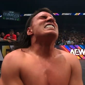 Speedball Mike Bailey is seen writhing in agony during a wrestling match against MJF on AEW Dynamite, with a referee observing nearby. The audience is visible in the background, reacting to the intense moment.