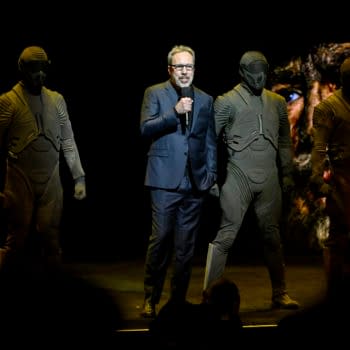 Denis Villeneuve speaks onstage at CinemaCon 2026 with masked Dune characters standing around him.