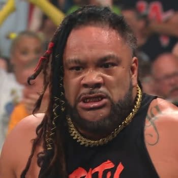 Jacob Fatu glares intensely in the WWE Raw ring, looking enraged after a chaotic moment. He wears a black sleeveless top and gold chain, with the crowd blurred behind him.
