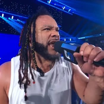 Jacob Fatu shouts into a WWE microphone on SmackDown, with the arena lights blazing behind him.