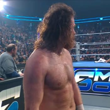 Sami Zayn stands at ringside during WWE SmackDown, looking away from Cody Rhodes after walking out on him. The crowd watches the tense moment unfold.