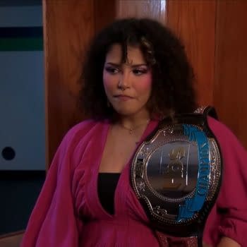 Willow Nightingale stands in a backstage hallway with the TBS Championship over her shoulder, looking serious and emotional.