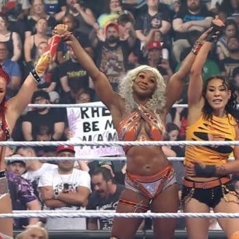 B-Fab, Jade Cargill, and Michin stand in the WWE SmackDown ring with their arms raised in celebration. A cheering crowd fills the background.