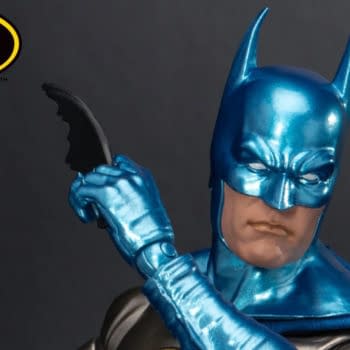 Batman action figure in a metallic blue suit and cowl, posed with a batarang against a dark background. A Beast Kingdom Exclusive 2026 badge and Batman logo appear in the corners.